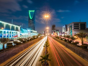 La tour du Royaume, à gauche, se dresse le long de l'autoroute King Fahd, éclairée par les traînées lumineuses du trafic de passage, à Riyad, en Arabie saoudite.