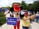 A person wearing a mouse costume takes selfies with supporters of Florida's Republican-backed 