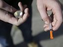 Dans cette photo d'archive du 22 octobre 2018, un utilisateur de fentanyl tient une aiguille près de Kensington Ave. et East Cambria St. à Philadelphie