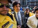 Const. de police de Toronto  Robert Konashewych – à gauche et le plus proche de la caméra – est représenté sur une photo du 11 mai 2016.  La photo n'a aucun rapport avec le procès en cours de Konashewych.  La photo montre l'ancien animateur de radio de la CBC, Jian Ghomeshi, alors qu'il se rend au palais de justice de Toronto où il a signé un engagement de ne pas troubler l'ordre public et s'est excusé auprès d'un plaignant.  La Couronne a ensuite retiré une accusation d'agression sexuelle contre Ghomeshi.