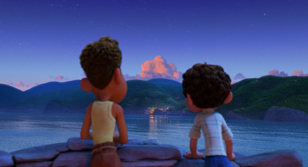 Luca et Alberto regardant une ville de l'autre côté de l'eau le soir