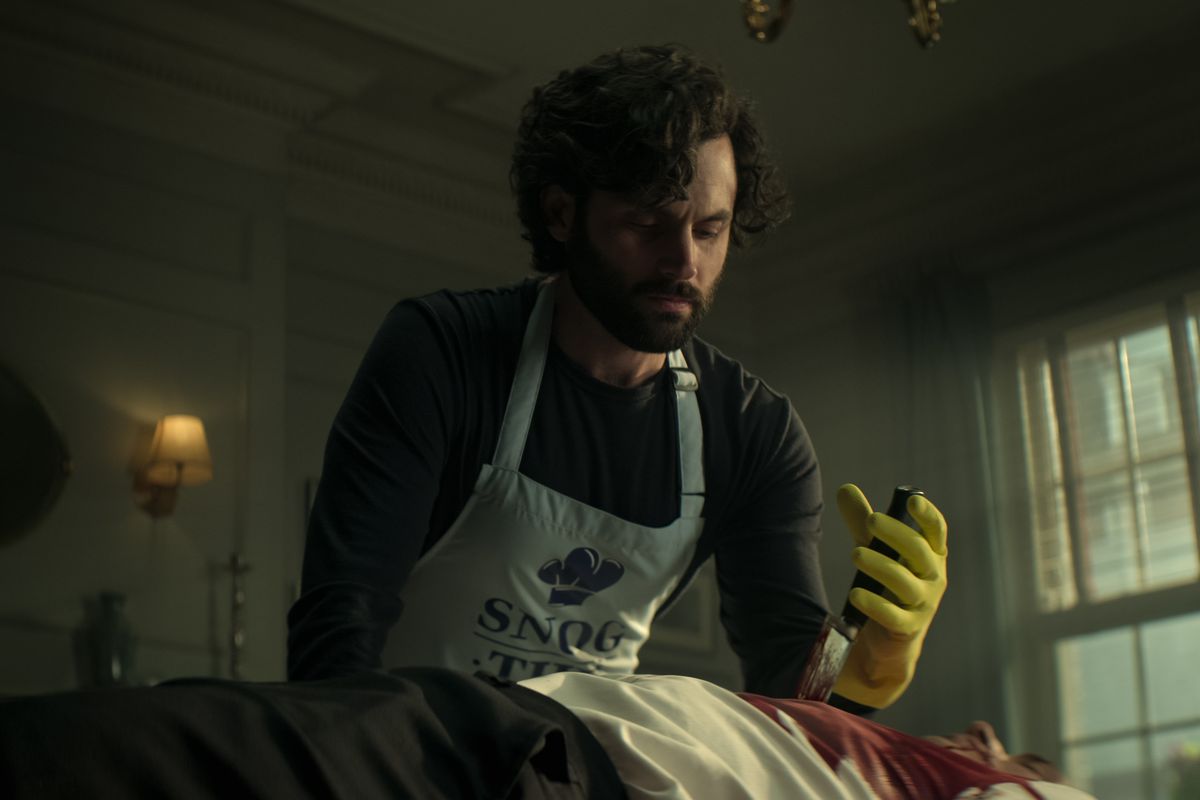 Penn Badgley dans le rôle de Joe Goldberg en train de retirer un couteau de la poitrine d'un homme mort dans You saison quatre.