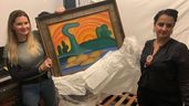 L'enquêteur de la police civile et un délégué tiennent une peinture intitulée 