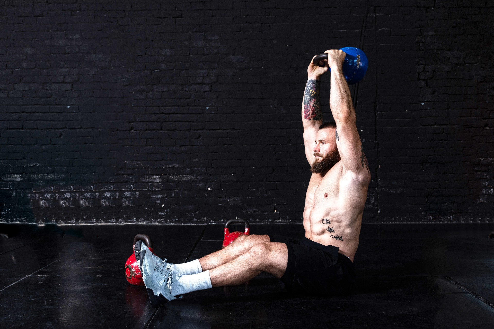 Homme exécutant un sit-up tenant un kettlebell au-dessus de sa tête