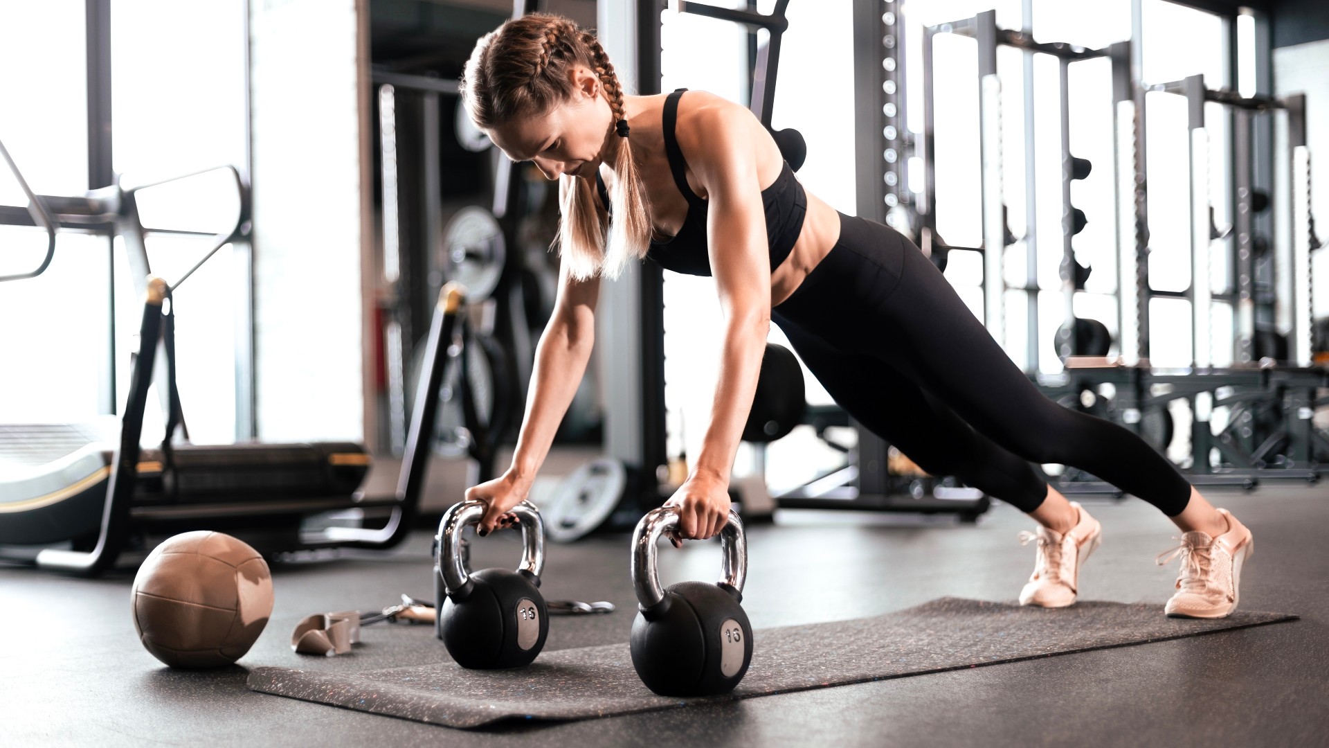 Femme exécutant une rangée de renégats à l'aide de deux kettlebells