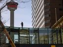 Un homme nettoie l'extérieur d'un passage à niveau Plus-15 au-dessus de la rue Centre au centre-ville de Calgary le samedi 3 avril 2021.