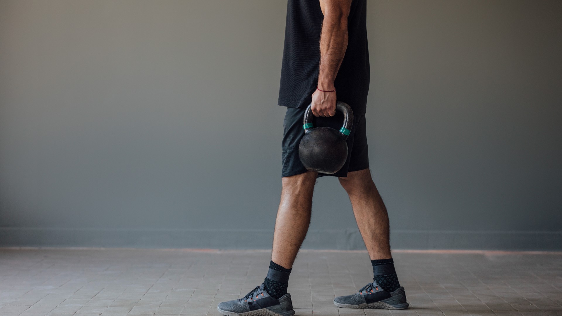 Homme marchant tenant deux kettlebells dans la marche de l'agriculteur