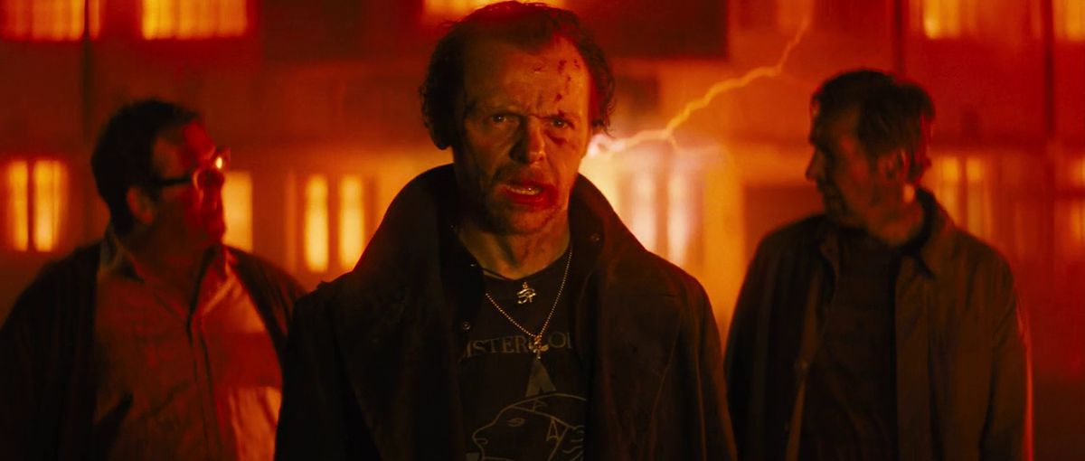 Trois hommes à l'air hagard (LR Nick Frost, Simon Pegg, Eddie Marsan) s'éloignent d'un bâtiment illuminé d'éclairs rouges dans The World's End.