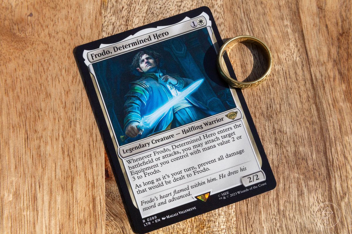 Une carte Magic: the Gathering de Frodon, héros déterminé à côté d'une réplique de The One Ring.