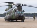 Un membre de l'Aviation royale canadienne observe alors qu'un CH-147 Chinook se prépare à décoller le 10 avril 2021 à Thompson, au Manitoba, au cours de l'opération VECTOR. 