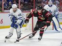 Le défenseur des Maple Leafs Mark Giordano (55) et Drake Batherson (19) des Sénateurs se battent pour la rondelle en première période.