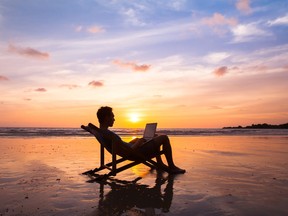 Une personne travaillant sur un ordinateur portable sur la plage.