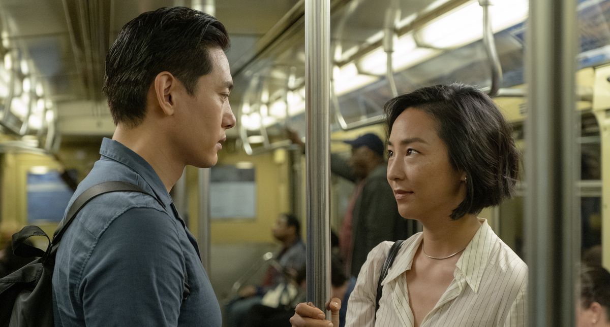 Nora et Hae Sung dans le métro, se regardant fixement alors qu'ils tiennent le poteau central.