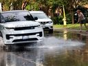 Inondations sur la Première Avenue à Ottawa lundi après une violente tempête de pluie.  Kim Saravanamuttoo essaie de dégager sa grille d'égout pour maintenir le niveau d'eau bas dans sa rue.