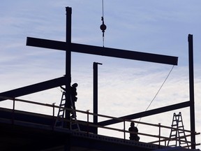 Les travailleurs guident et fixent les poutres en acier au sommet d'un bâtiment pendant la construction