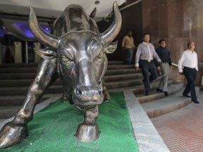 Les gens passent devant la statue de taureau en bronze à l'entrée du bâtiment de la Bourse de Bombay à Mumbai en Inde.  Les actions indiennes sont sous-estimées, disent les analystes.