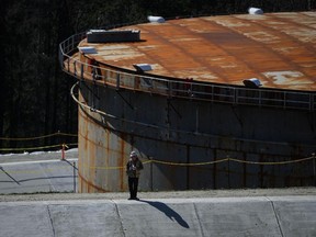 Un travailleur se tient debout sur une berme en béton au projet d'agrandissement du pipeline Trans Mountain au parc de stockage du terminal de Burnaby à Burnaby, en Colombie-Britannique, en mars.