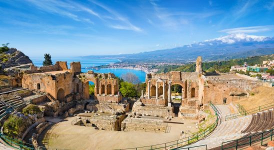 Ruins of Ancient Greek theatre in Taormina on background of Etna Volcano, Italy. Taormina located in Metropolitan City of Messina, on east coast of island of Sicily.