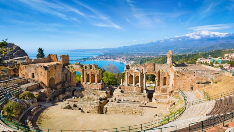 Ruins of Ancient Greek theatre in Taormina on background of Etna Volcano, Italy. Taormina located in Metropolitan City of Messina, on east coast of island of Sicily.