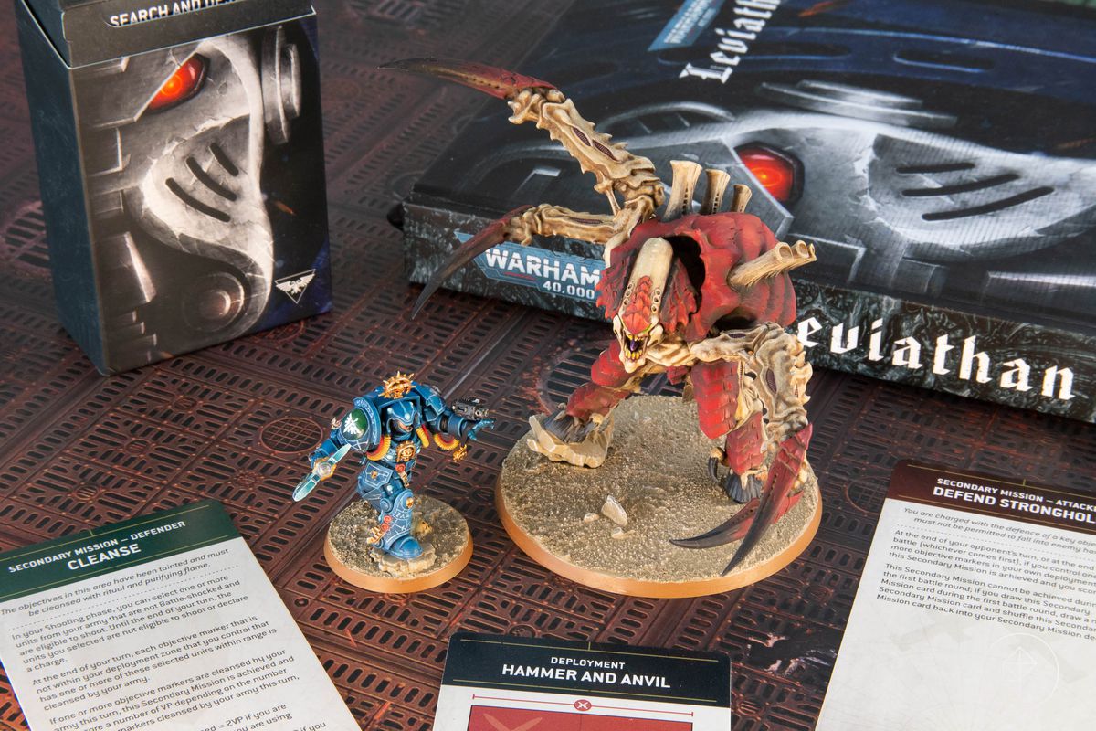 Le coffret complet Warhammer 40,000 : Leviathan comprend 72 figurines, présentées ici sur un terrain en plastique non fourni avec le coffret.  Les Space Marines sont bleus et les Tyrannids sont violets et roses.  La scène se déroule le long d'un grand rempart.