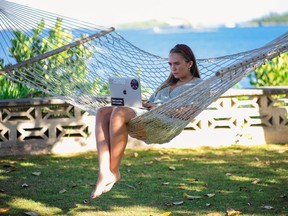 Une femme travaillant sur un ordinateur portable sur un hamac aux Bermudes.