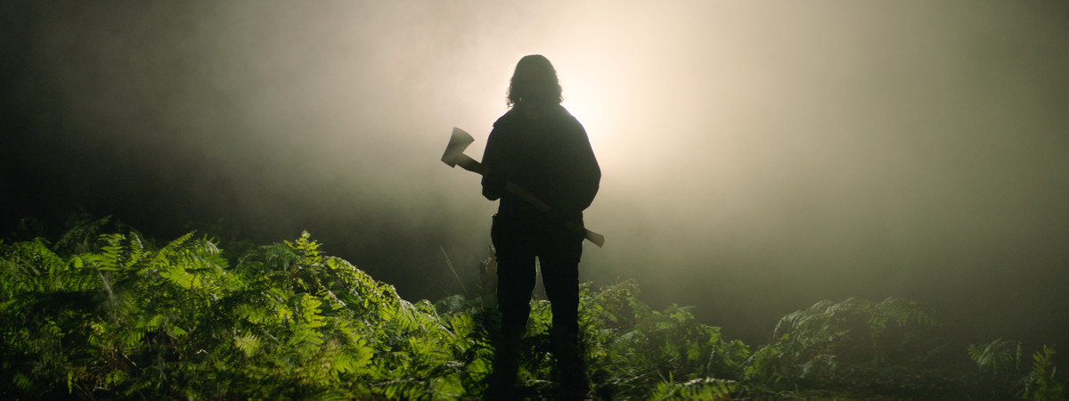 Une silhouette dans la forêt, tenant une hache, dans In the Earth