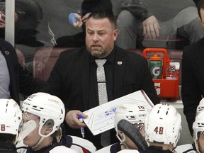 L'entraîneur-chef des Spitfires de Windsor, Marc Savard, passe en revue un jeu pendant un temps mort.