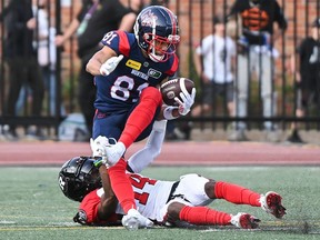 Les Alouettes reçoivent Austin Mack est plaqué par le demi défensif des Rouge et Noir Abdul Kanneh dans la première moitié du match de samedi à Montréal.