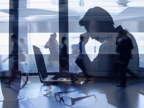 Silhouette d'un homme d'affaires fatigué devant un ordinateur portable au bureau.