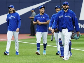 Le lanceur partant des Blue Jays de Toronto, Alek Manoah, à droite, se dirige vers la pirogue avec ses collègues lanceurs partants Kevin Gausman, de gauche à droite, Jose Berrios et Yusei Kikuchi avant l'action de baseball de la MLB contre les Milwaukee Brewers à Toronto le mercredi 31 mai 2023. LA PRESSE CANADIENNE/Frank Gunn