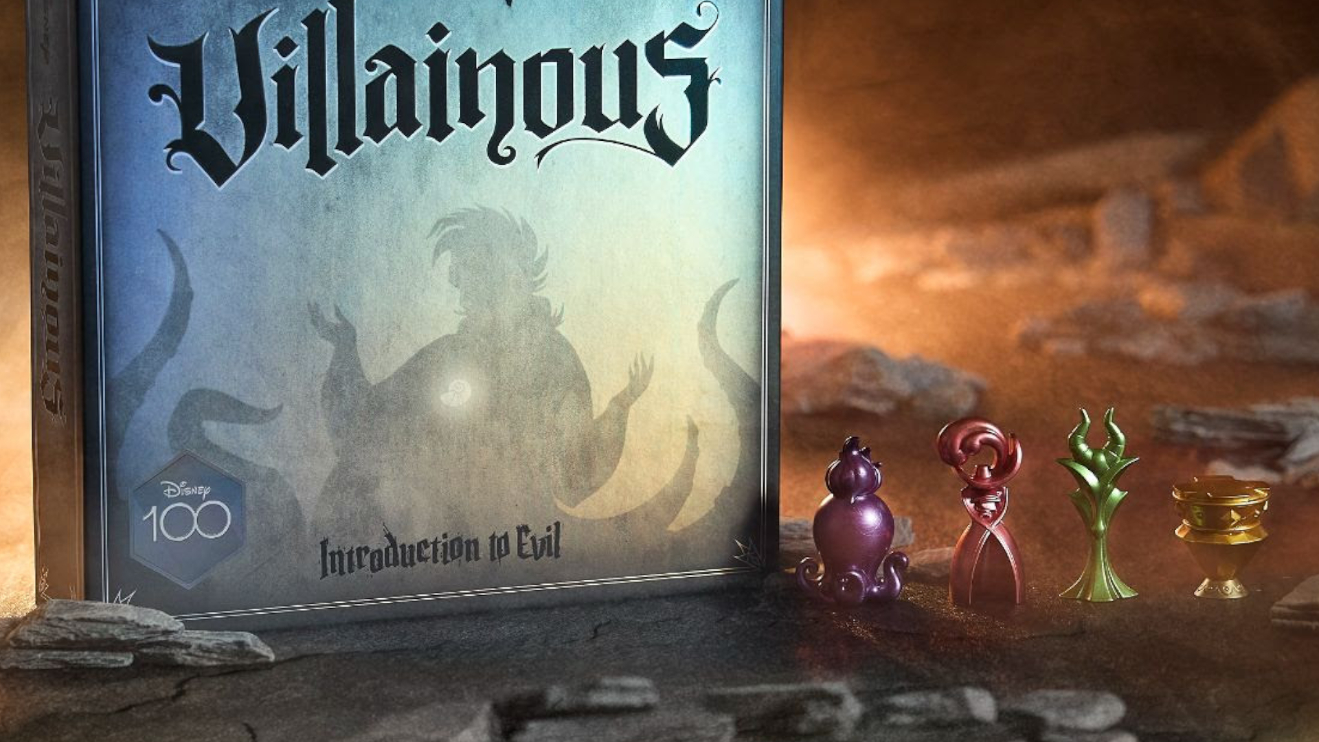 La boîte et les jetons Disney Villainous: Introduction to Evil (Disney100 Edition) sur un sol rocheux