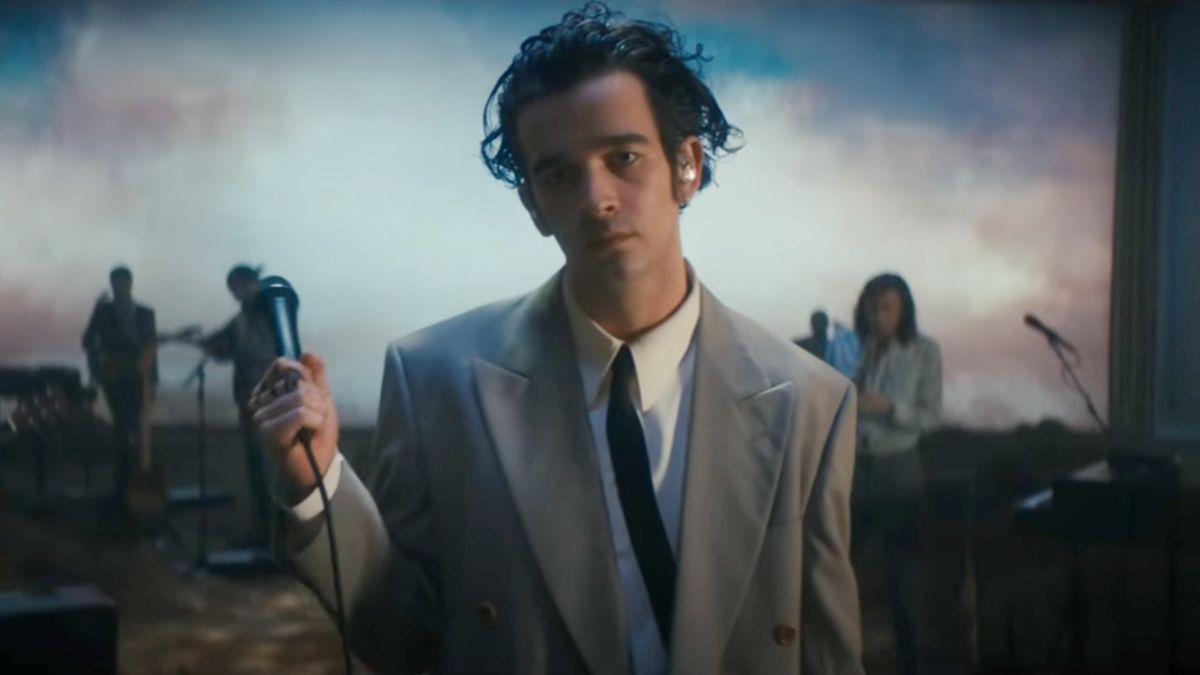 Matty Healy holding a mic in the Part of the Band performance by The 1975.