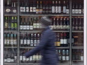 Une personne passe devant des étagères de bouteilles d'alcool exposées dans une LCBO à Ottawa.