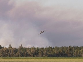 Un bombardier à eau vole vers un important feu de champ et de forêt au Québec en 2020.