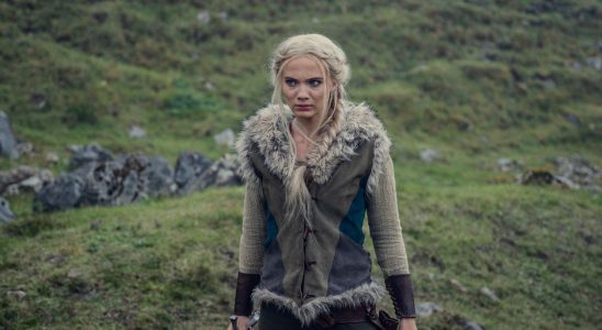 Ciri (Freya Allan) stands with a sword in the open countryside