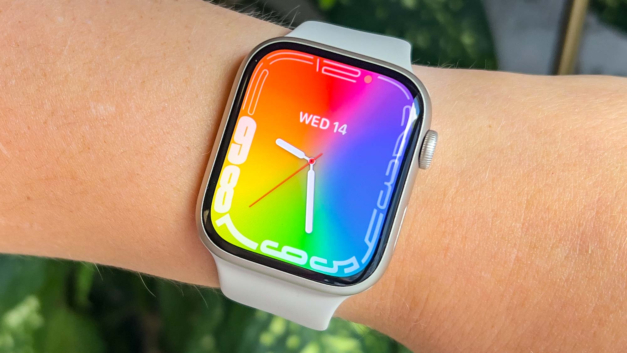 Apple Watch 8 au poignet avec un papier peint coloré