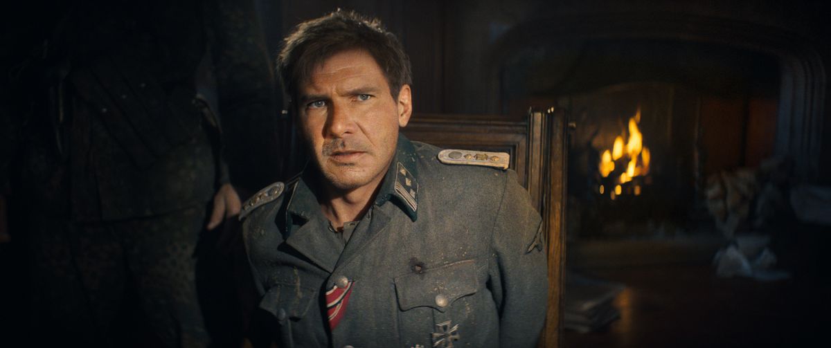 Harrison Ford dans le rôle d'Indiana Jones, paraissant âgé d'environ 40 ans en raison du vieillissement de CG et portant un costume gris avec des détails aléatoires en tissu drapeau américain, semble très préoccupé par quelque chose qui se passe hors écran dans Indiana Jones et le cadran du destin