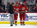 L'entraîneur sportif en chef des Hurricanes de la Caroline Doug Bennett, à gauche, et Brent Burns, à droite, assistent Max Pacioretty hors de la glace à la suite d'une blessure au cours de la troisième période du match de hockey de l'équipe de la LNH contre le Wild du Minnesota à Raleigh, en Caroline du Nord, le jeudi 19 janvier. 2023.