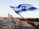 Des Israéliens agitent leurs drapeaux nationaux lors d'une marche à côté du Mur Occidental à Jérusalem.