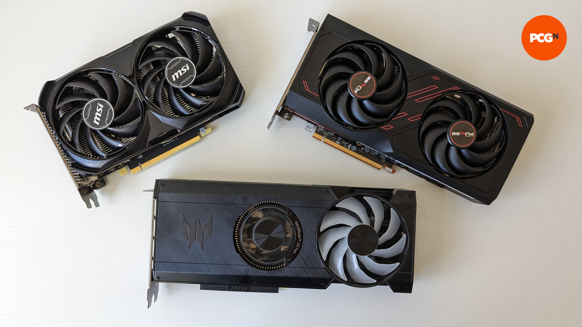 Revue Nvidia GeForce RTX 4060 : Le GPU (en haut à gauche) se trouve sur une surface blanche à côté du RX 7600 (en haut à droite) et de l'Intel Arc A770 (en bas)