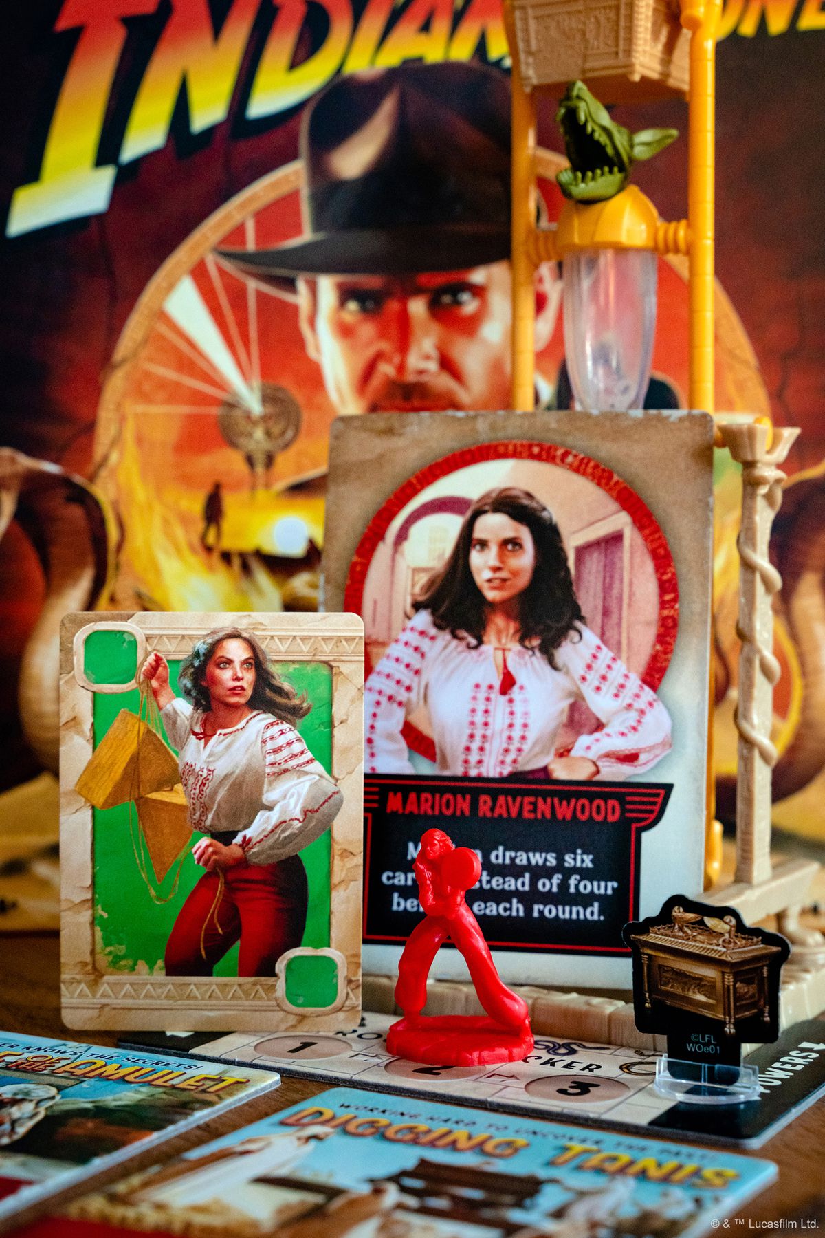 Une carte pour Marion Ravenwood, et une miniature rouge.  L'image montre également un déménageur en carton en forme de 