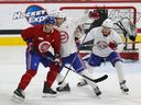 Le choix de premier tour des Canadiens au repêchage David Reinbacher (centre en blanc) affronte le défenseur Charle Trouchon au camp de perfectionnement des Canadiens avec leurs meilleurs espoirs au Complexe sportif Bell à Brossard le dimanche 2 juillet 2023. À droite se trouve Lane Hutson.