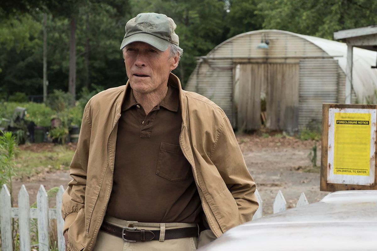 Clint Eastwood portant une chemise marron, une veste beige, un pantalon beige et un chapeau gris dans The Mule.