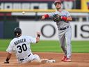 Whit Merrifield, à droite, des Blue Jays de Toronto lance au premier but pour terminer un double jeu après avoir expulsé Jake Burger des White Sox de Chicago au deuxième but lors de la troisième manche au champ de taux garanti le mardi 4 juillet 2023 à Chicago .  