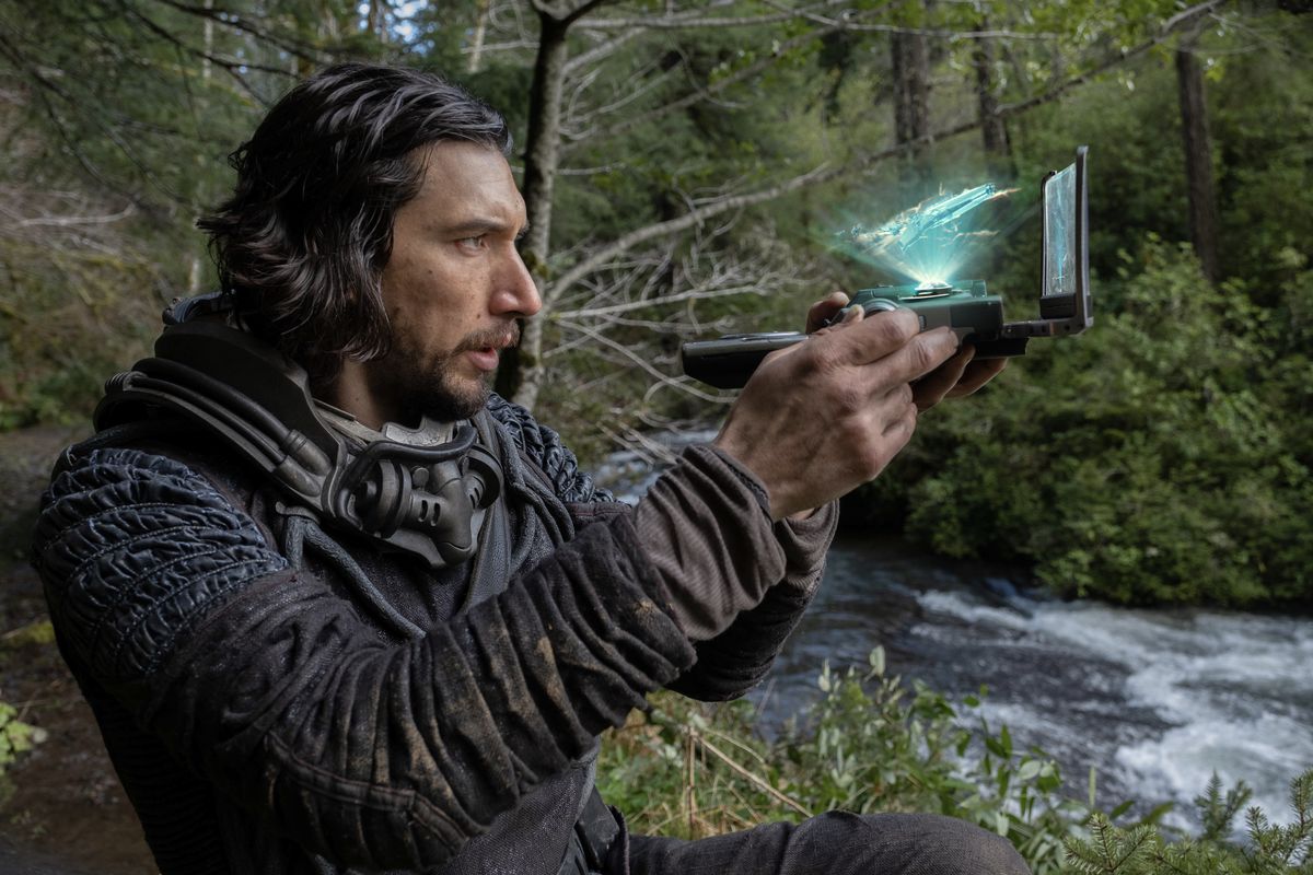 Adam Driver's Mills brandit un hologramme 3D de son vaisseau alors qu'il navigue dans les jungles préhistoriques de la Terre en 65