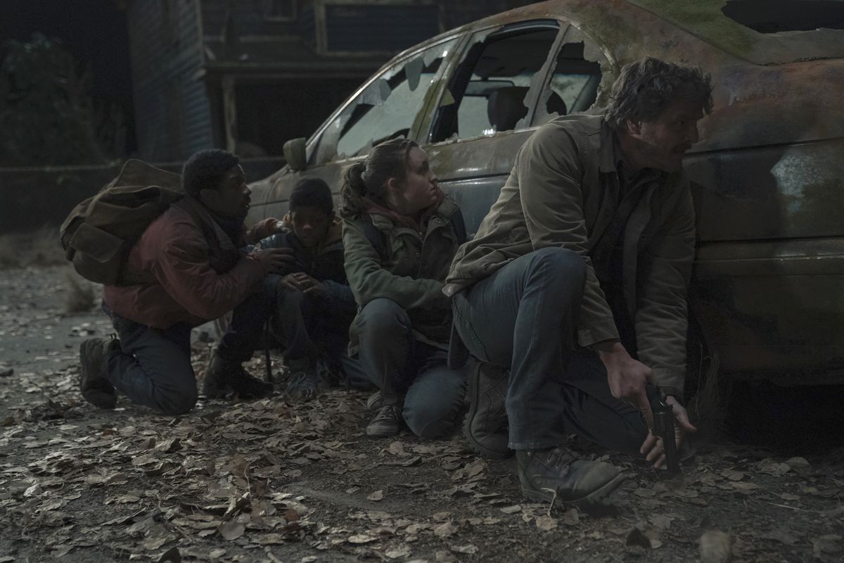 Joel (Pedro Pascal), Ellie (Bella Ramsey), Henry et Sam accroupis derrière une voiture