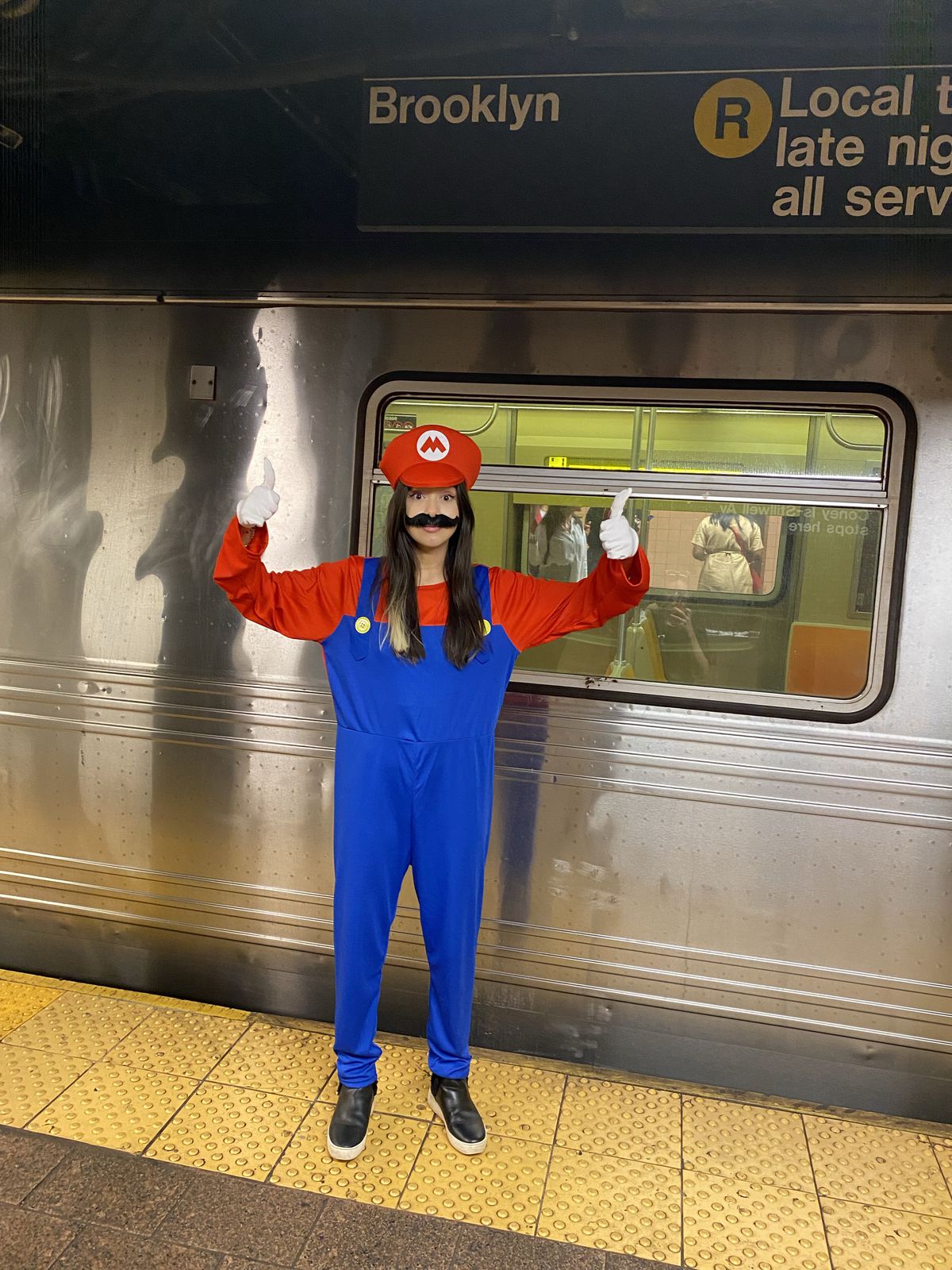 XTina GG dans un costume de mario donnant un double coup de pouce avant de sauter dans le métro pour Brooklyn