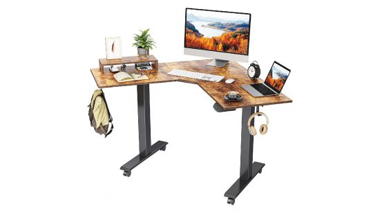 Le meilleur bureau debout d'angle est le Fezibo Dual Motor, avec un dessus de table en bois plus foncé et des pieds à cadre noir, vu ici avec un moniteur et un ordinateur portable assis dessus