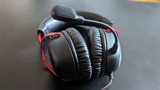 Avis HyperX Cloud 3 : un casque repose sur une table noire avec son microphone pointant vers le ciel.