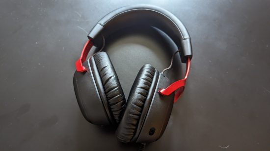 Avis HyperX Cloud 3 : une vue de haut en bas d'un casque noir et rouge sur une table noire avec un fort éclairage venant du dessus de l'image.